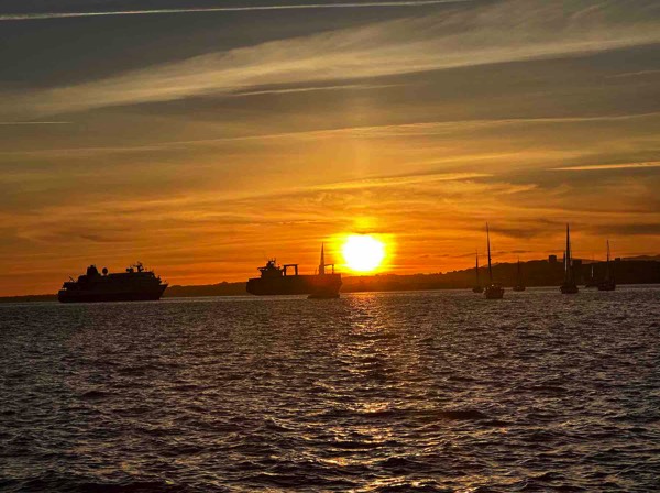 Photo of sunset on the Tagus river with yachts and sailboats on the water